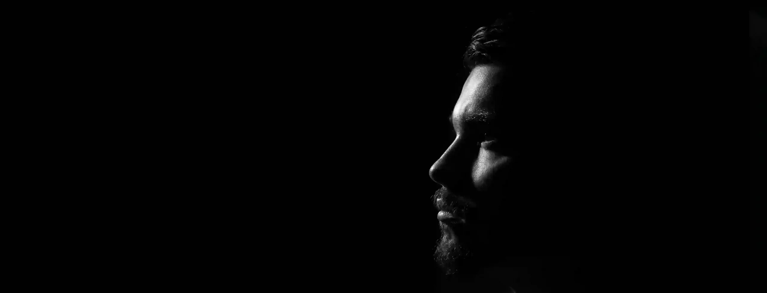 Silhouette of a man's profile with side lighting against a dark background.