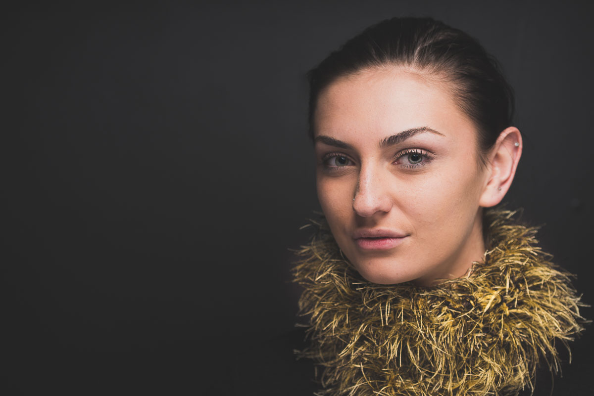 A woman wearing a gold scarf on a black background.