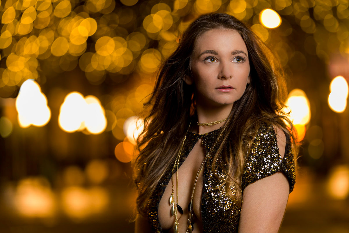 A woman in a sequin dress posing in front of lights.