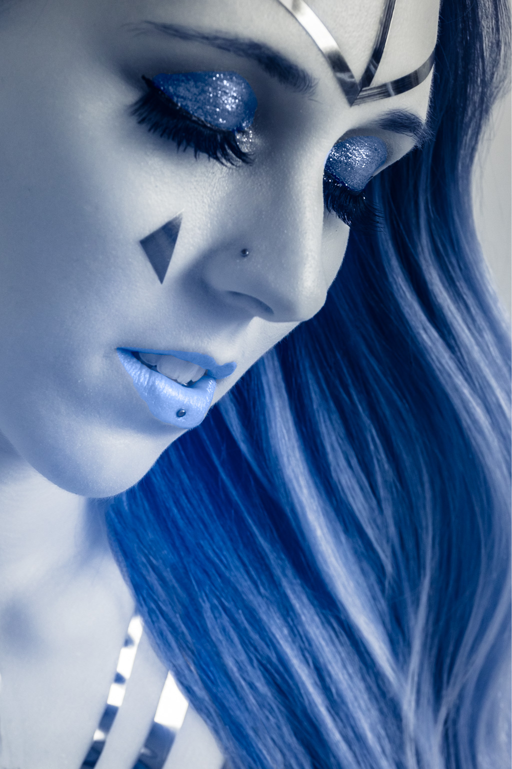 A woman with blue hair and silver makeup.