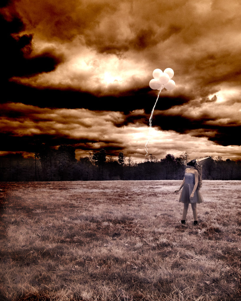 A person is flying a balloon in a field.