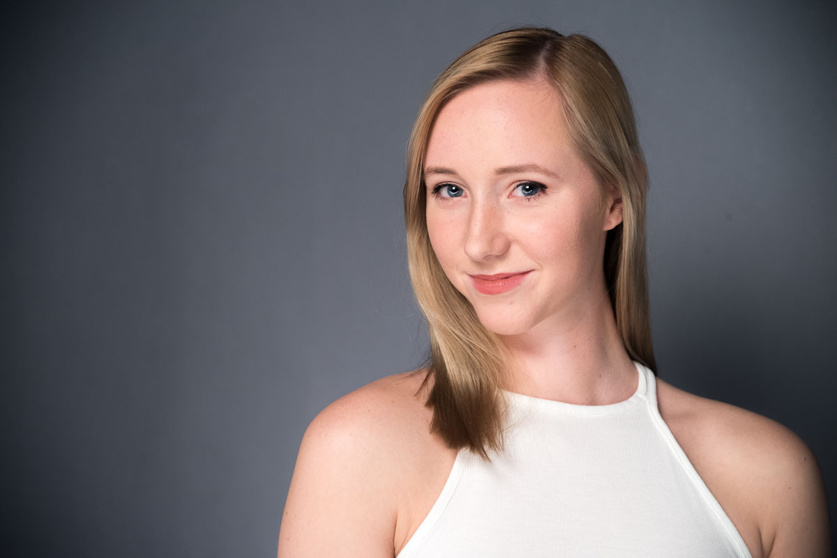 A woman in a white top posing for a photo at home.