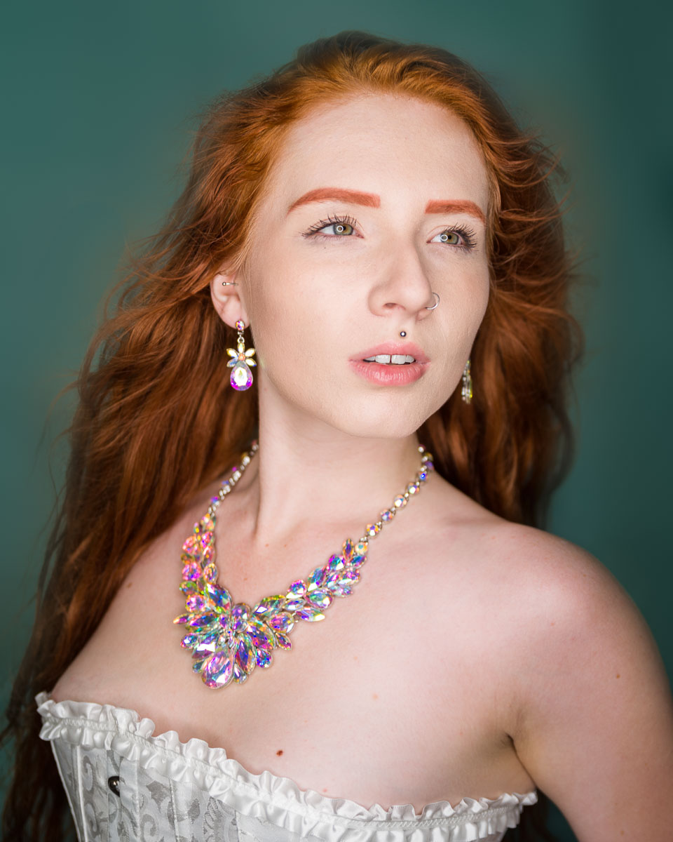 A woman with red hair wearing a colorful necklace.