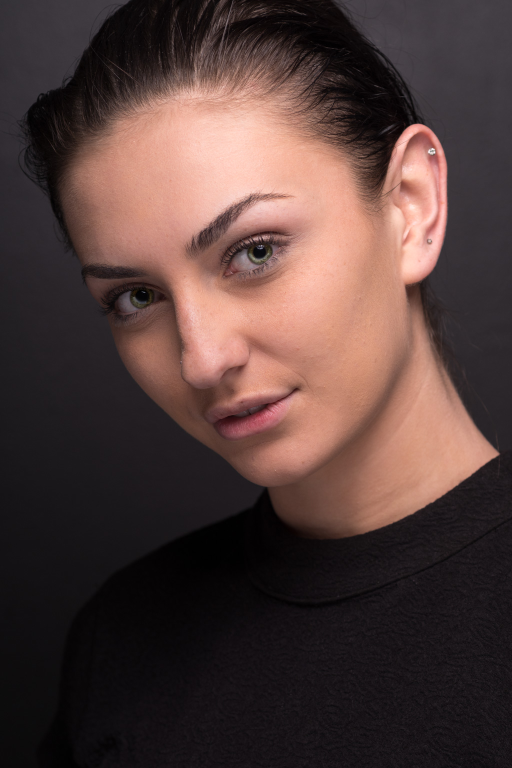 A young woman posing for headshots in a black t-shirt.