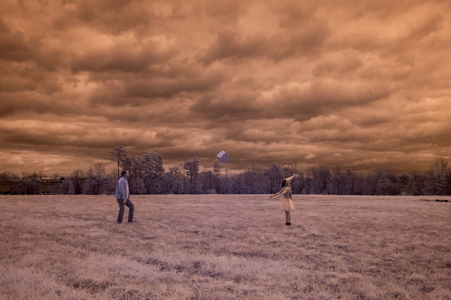 Two people joyfully celebrate a pandemic birthday by playing with a frisbee in a field under a cloudy sky.