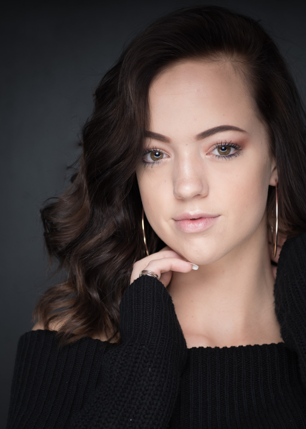 A young woman in a black sweater posing for a headshot portrait.