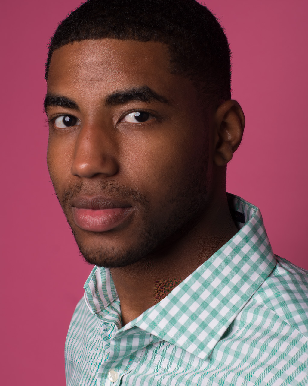 A young man wearing a green and white checkered shirt.