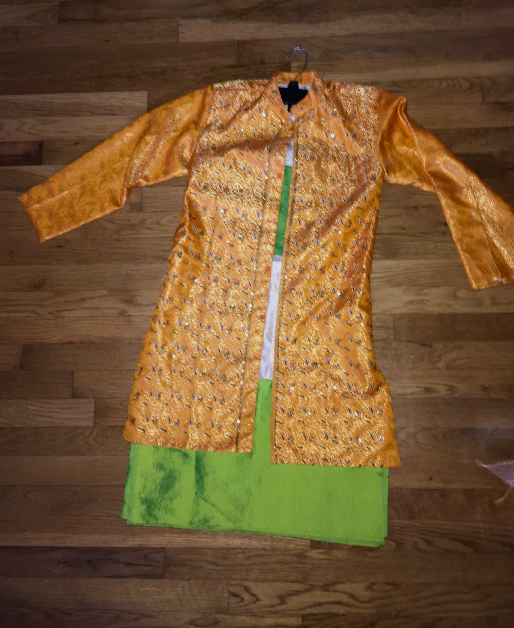 An orange and green kurta on a wooden floor.