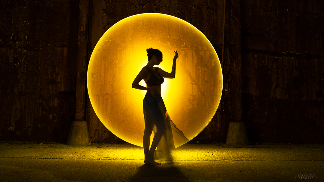 A woman standing in front of a circular light.