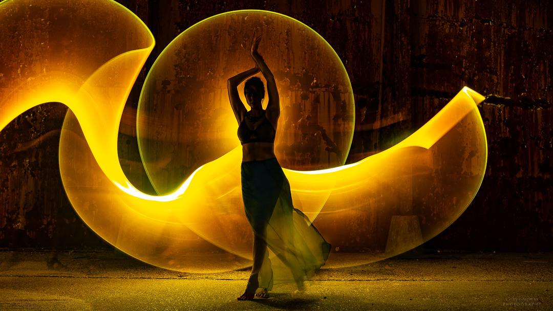 A woman is dancing in front of a yellow light.