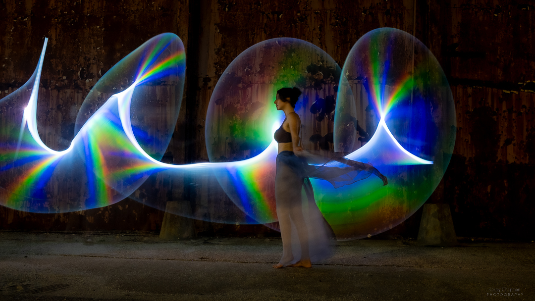 A woman is standing in front of an Auto Draft light sculpture.