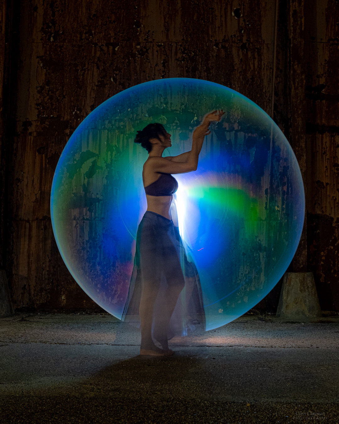 A woman is standing in front of a large bubble, mesmerized by its ethereal beauty.